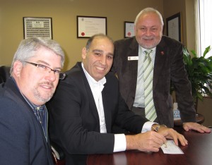 Tim Brown, left and Len Lifchus, both of the United Way,  lean just a little on Fund Raising Campaign Chair Karmel Sakran, center, to write a cheque for the amount to got the total to $2,200,00 - a record for Burlington.