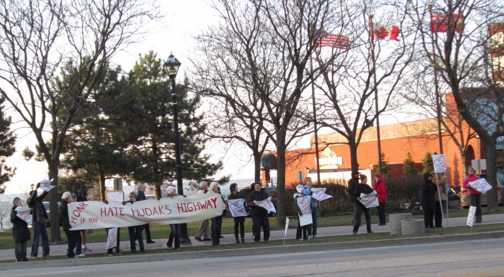 More than 50 demonstrators kept their banner stretched across the front of the Waterfront Hotel in Burlington Friday morning – asking the public to support their objective of keeping any kind of highway from running through the Escarpment