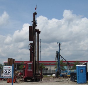Drilling rig that bores into the ground for the pipes that will be used to carry heat into the building.  Heat exchangers convert the heat into cool air during the summer months.