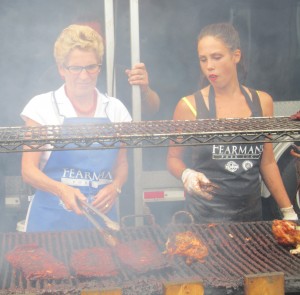 Part of Premier Kathleen Wynne"s on -the-job training as she learns to flip a rak of ribs at Ribfest.