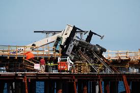 Crane working at the pier site topples.  Proves to be the pont at which problms with the design became evident.