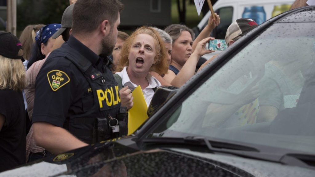 Protesters block Ontario Premier Doug Ford's car after the buck-a-beer plan announcement at Barley Days brewery in Picton, Ont., on Tuesday Aug. 7, 2018. THE CANADIAN PRESS/Lars Hagberg