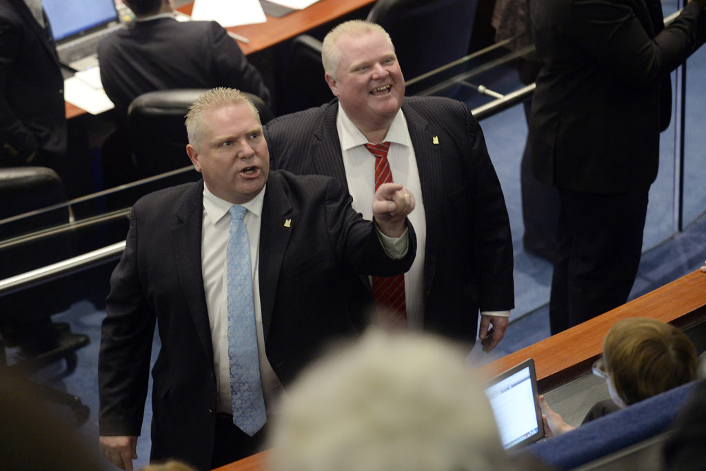 Toronto city councillor Doug Ford (L) and his brother, Mayor Rob Ford (L) react to the gallery after the mayor and an unidentified member of his staff captured images of the gallery during a special council meeting at City Hall in Toronto November 18, 2013. The Toronto city council may further curb the powers of embattled Mayor Rob Ford on Monday, slashing his office budget and offering his staff a chance to transfer to new jobs. (Aaron Harris/Reuters)