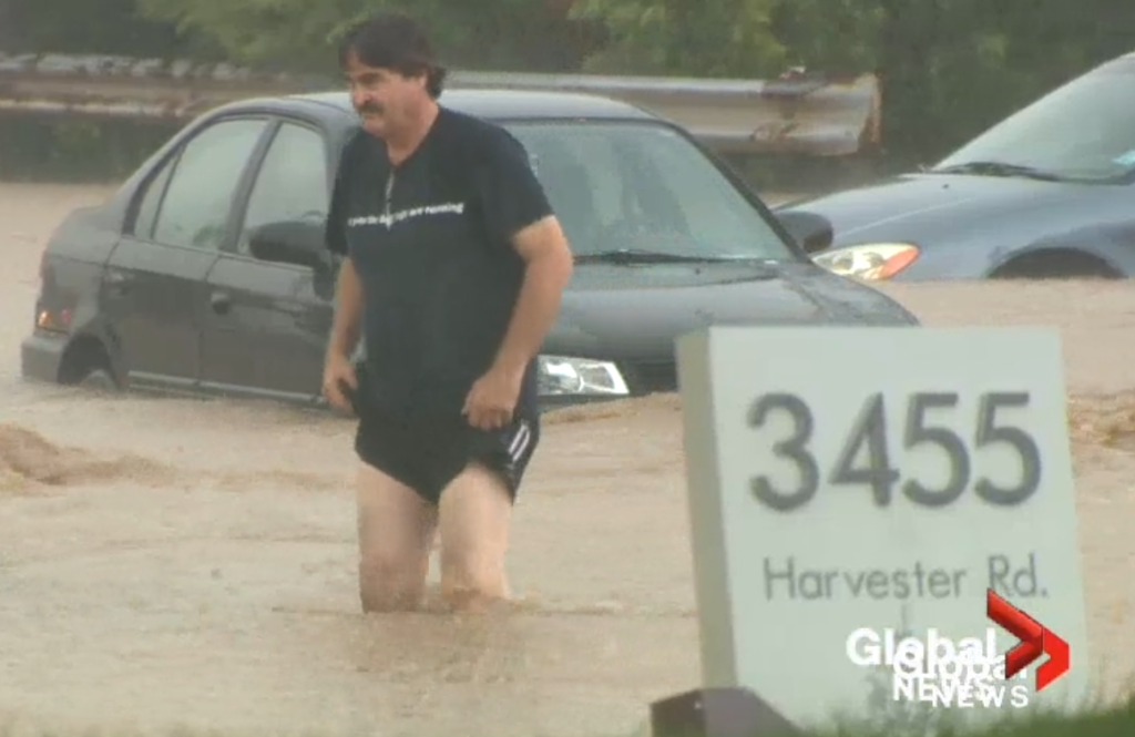 FLOOD man walking in water Harvester Road sign